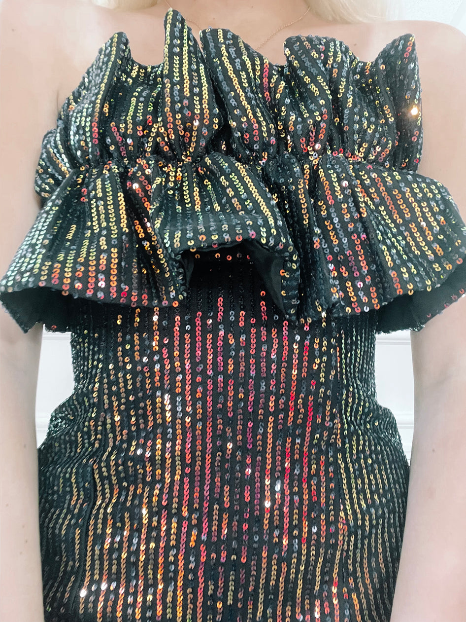 Sequined mini dress with ruffled off-the-shoulder neckline; multicolored sequins on black fabric.
