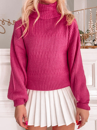 Pink ribbed turtleneck sweater styled with a white pleated skirt.
