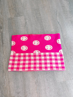 Pink and white knit scarf featuring a fun smiley face and houndstooth pattern.
