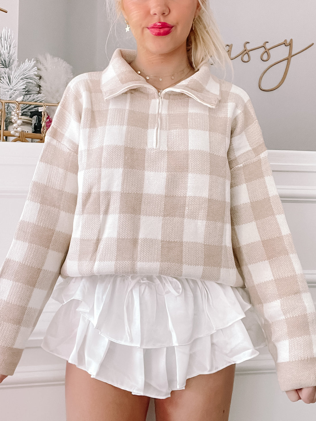 Beige and white gingham zip-up sweater styled with a white ruffle skirt.
