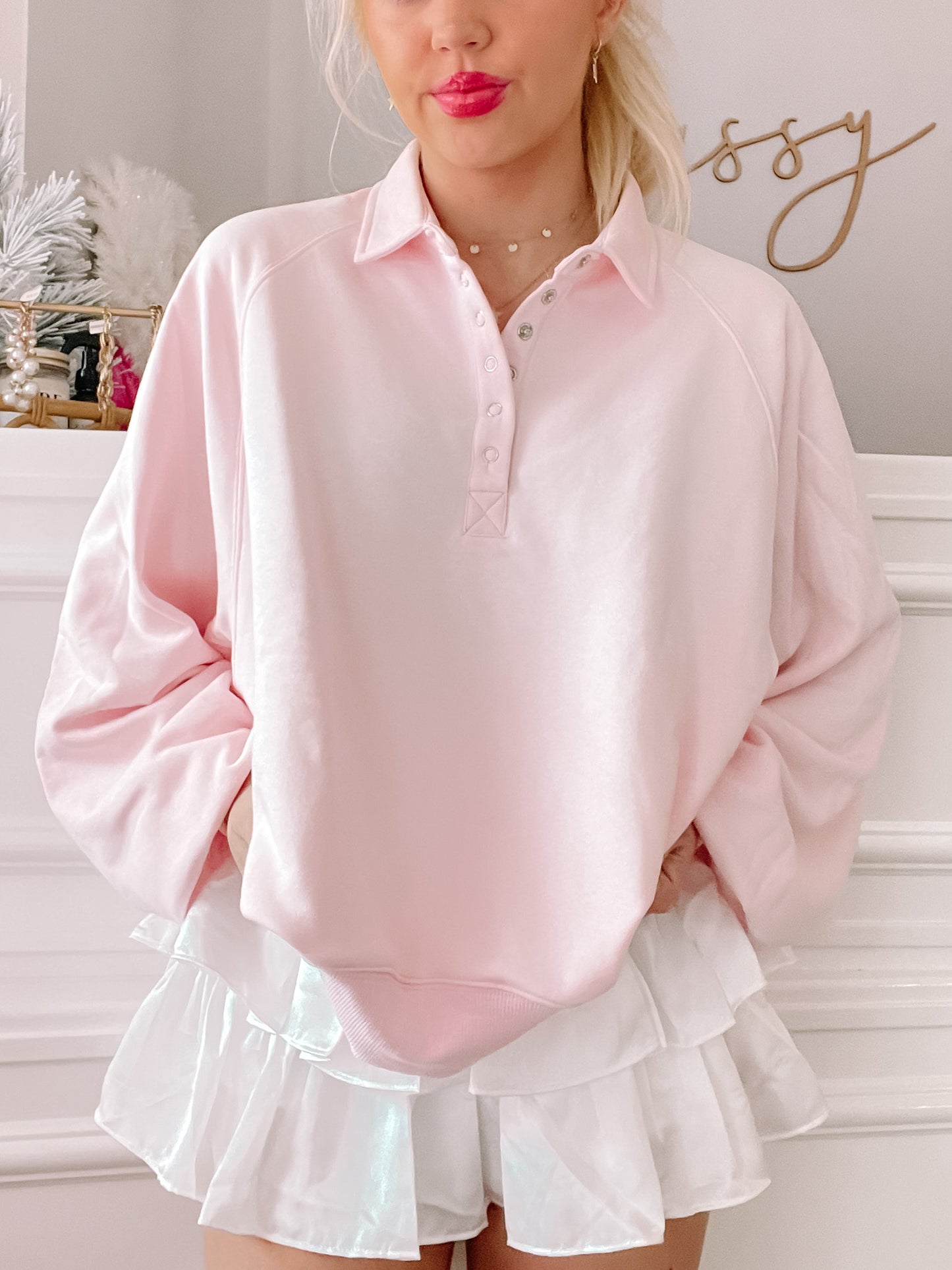 Pink pullover with button placket, modeled with white ruffle skirt.
