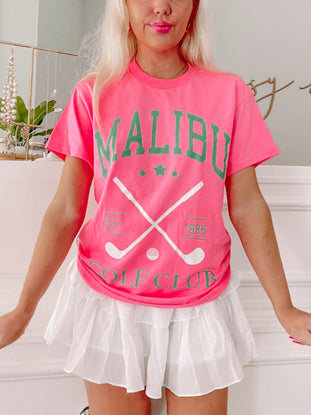 Pink Malibu Golf Club tee shirt featuring crossed golf clubs and "Est. 1986" graphic.
