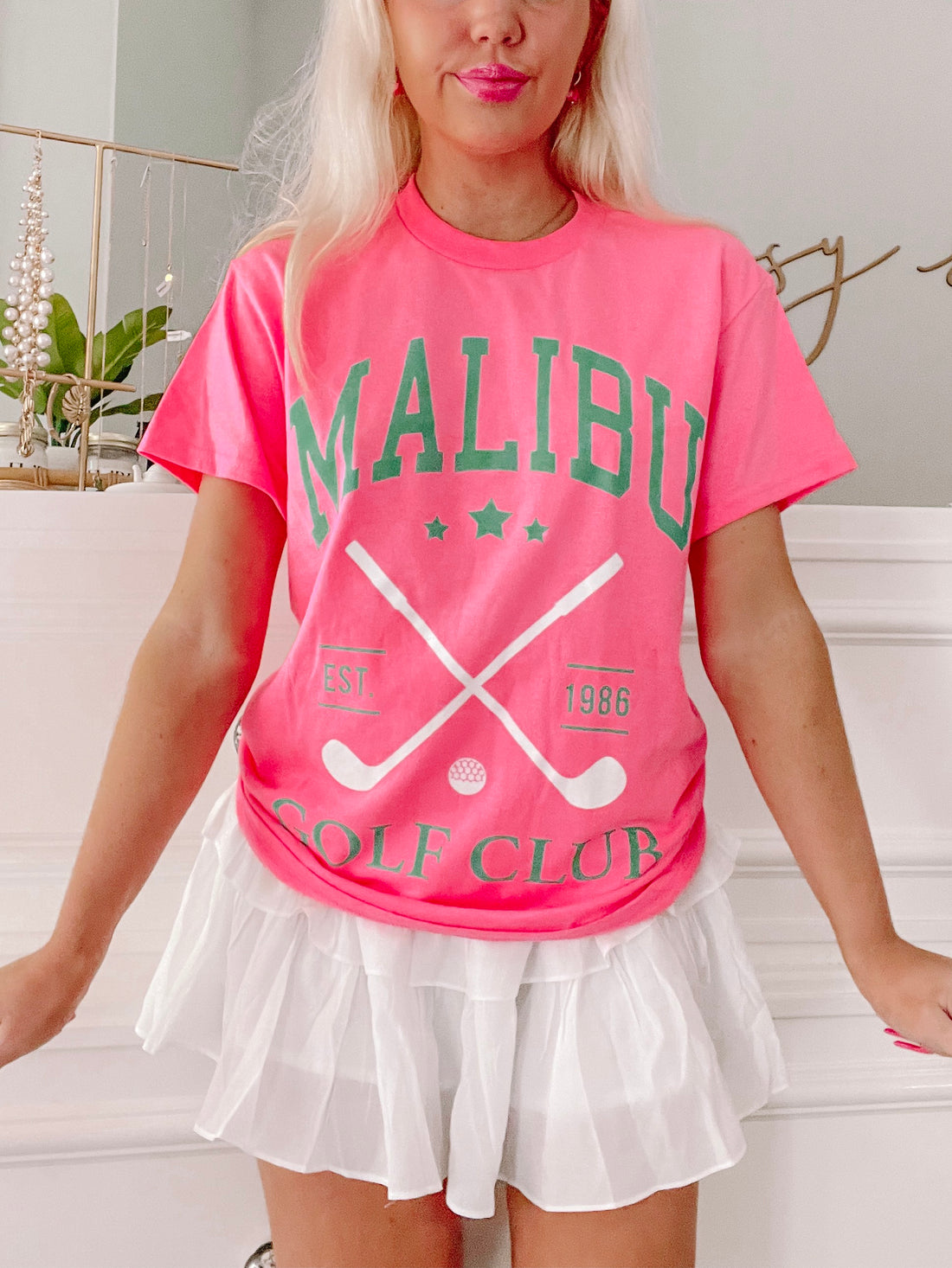 Pink Malibu Golf Club tee shirt featuring crossed golf clubs and "Est. 1986" graphic.
