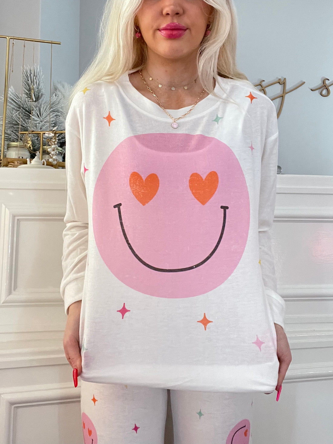 White pajama top featuring a pink smiley face with heart eyes, accented with pastel stars.
