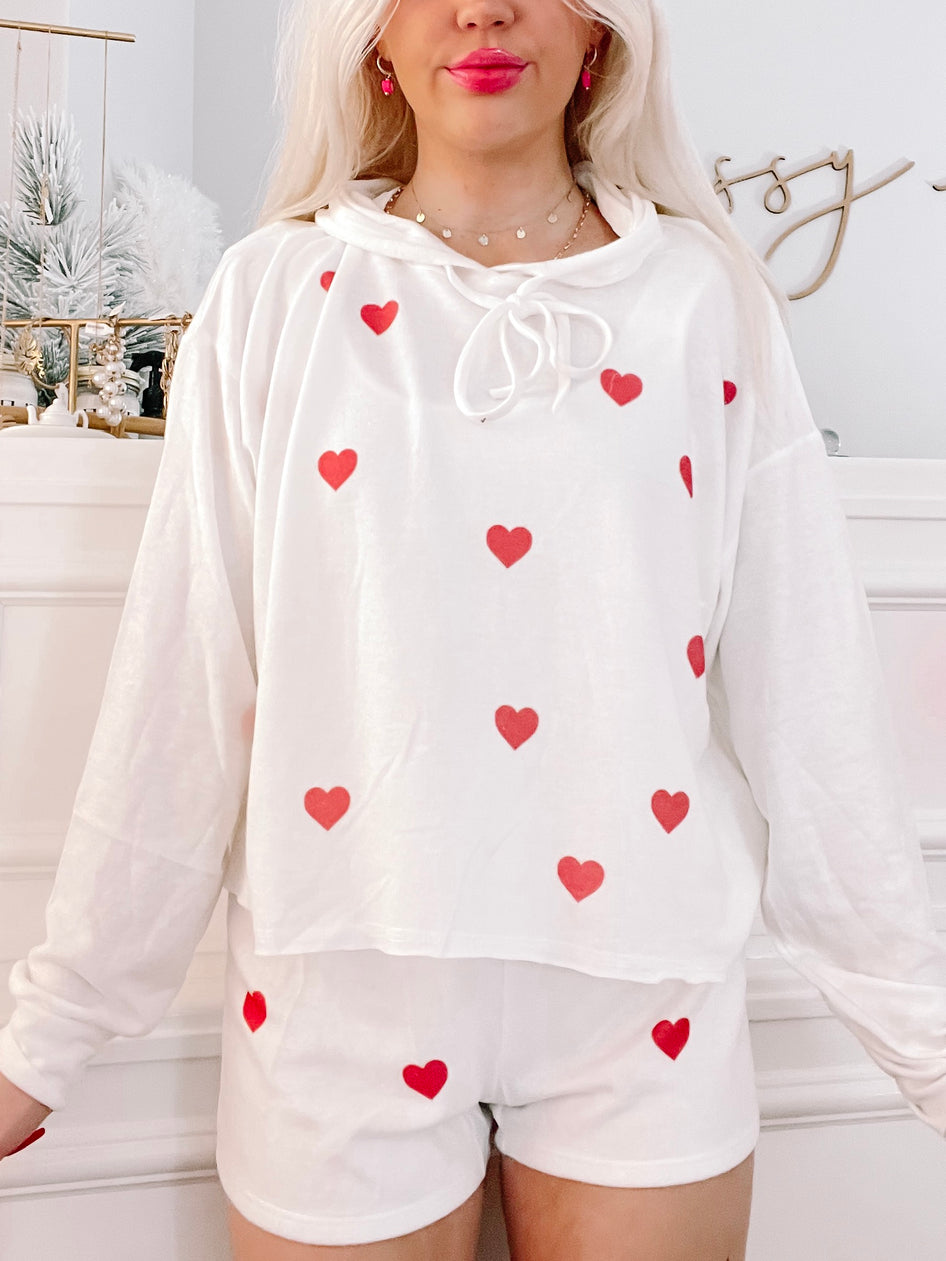 White pajama set with red heart pattern; comfy loungewear.

