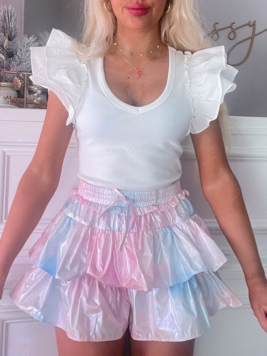Pastel rainbow iridescent mini skirt with ruffled layers, worn with a white ruffled top.