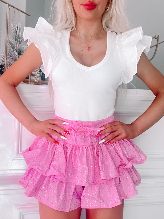 Pink rhinestone mini skirt with tiered ruffles, styled with a white top.