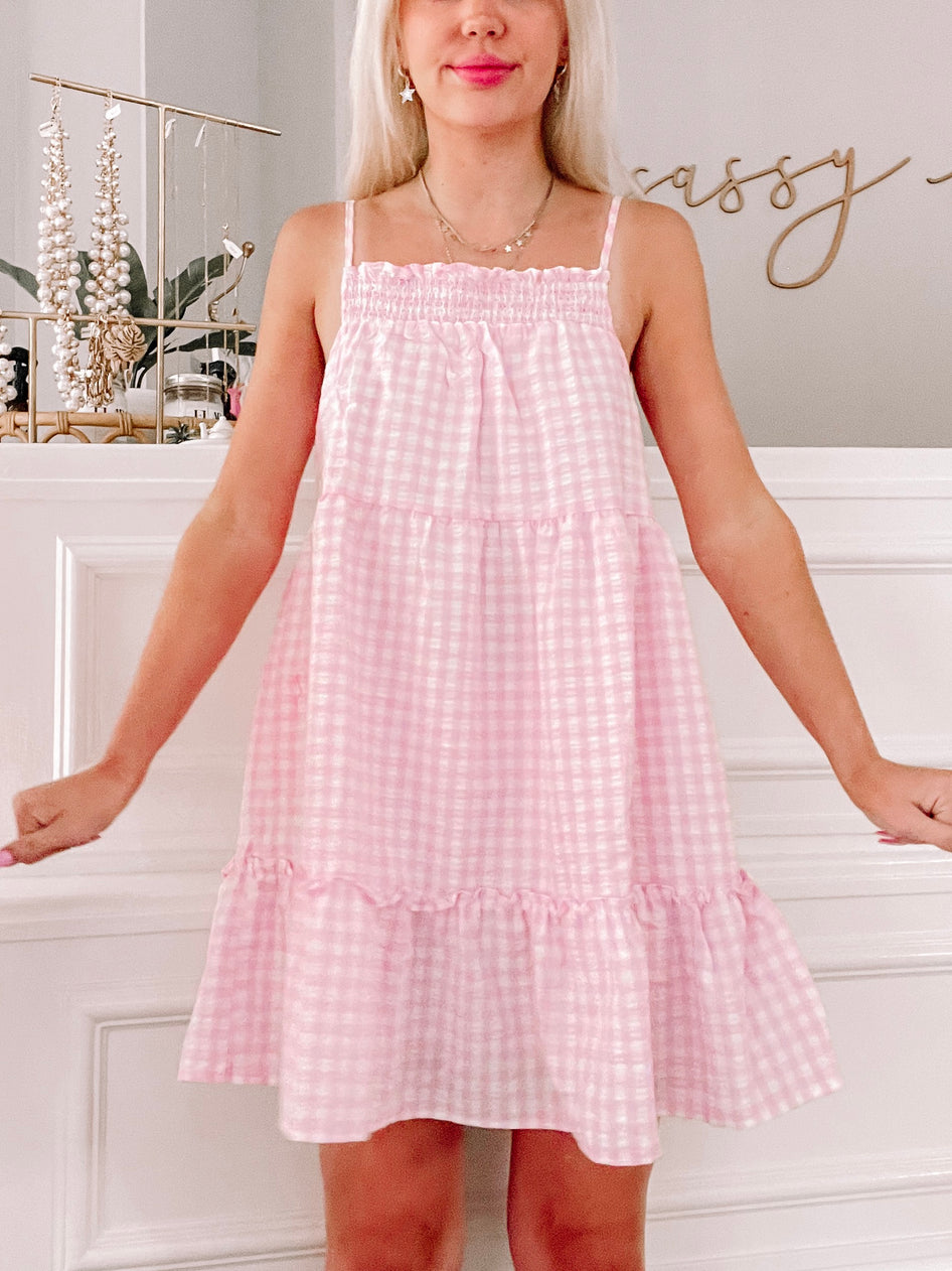 Pink gingham tiered mini dress; perfect summer style.
