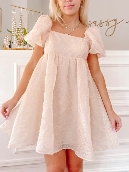 Cream-colored mini dress with puff sleeves, textured fabric, and a square neckline.
