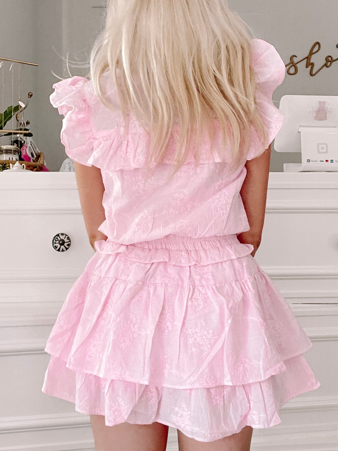 Pink tiered ruffle dress with delicate floral print, shown from the back.
