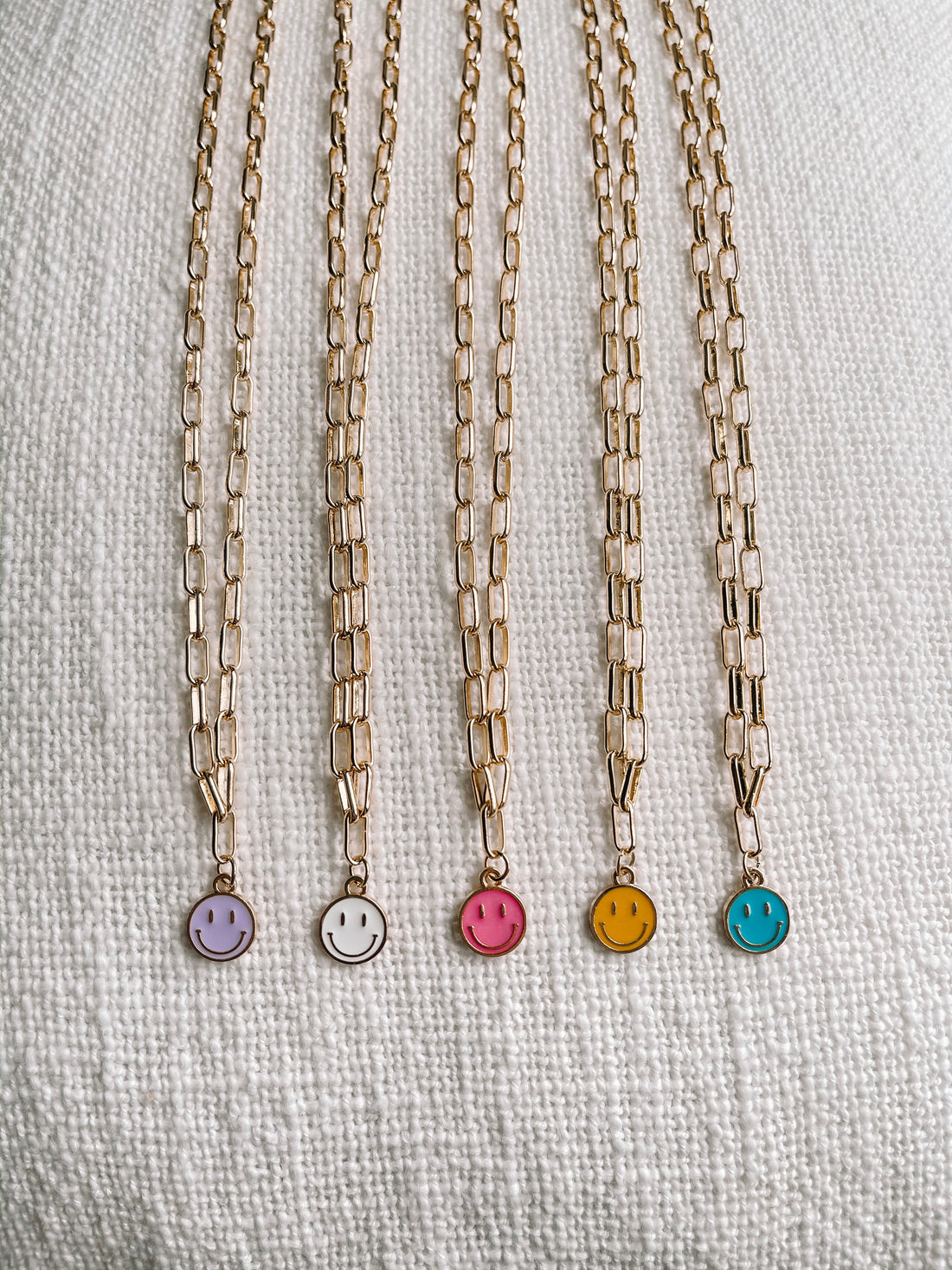 Happy Smiles gold chain necklaces with enamel smiley face charms in assorted colors.
