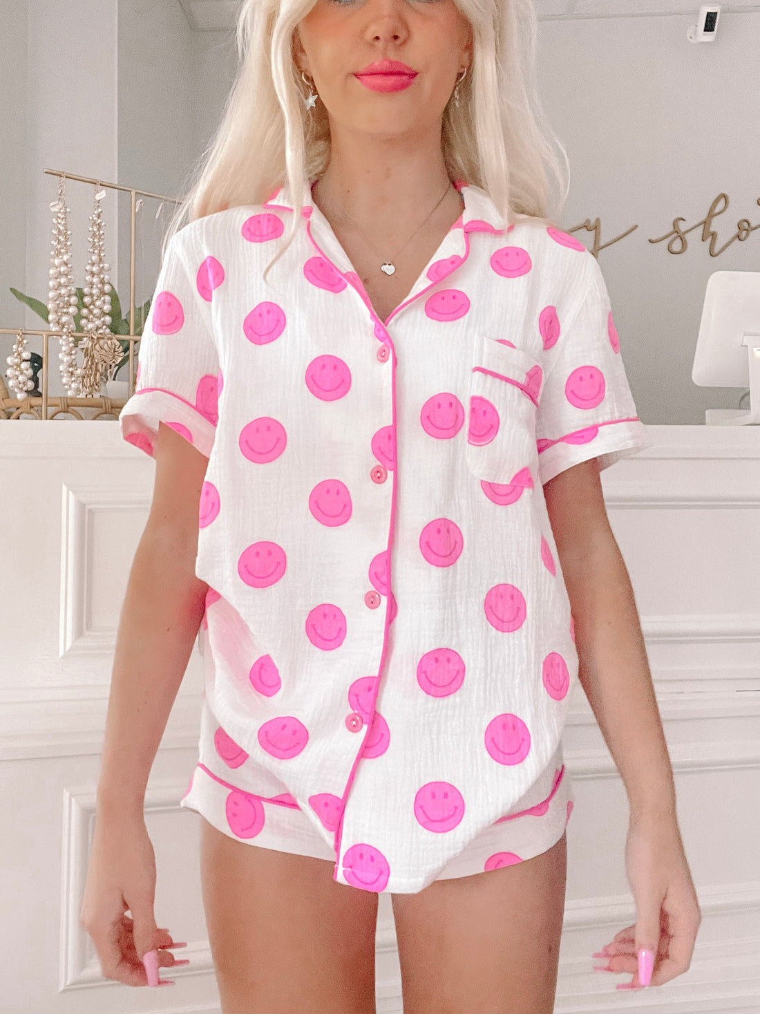 Pink smiley face pajama set; short-sleeved top and shorts, white background.
