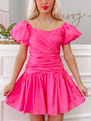 Hot pink mini dress with puff sleeves and a fitted bodice, shown on a model.
