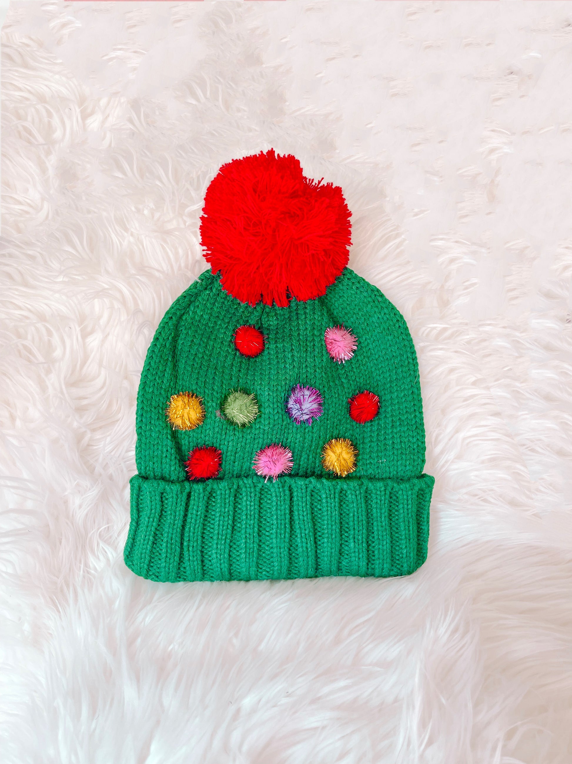 Green knit Oh Christmas Tree beanie with colorful pom-poms and large red pom-pom top.
