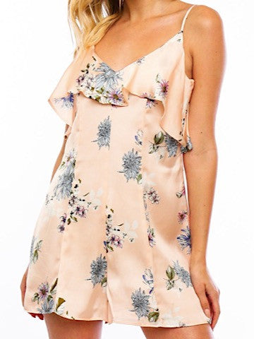 Peach satin romper with a floral print and ruffled neckline.
