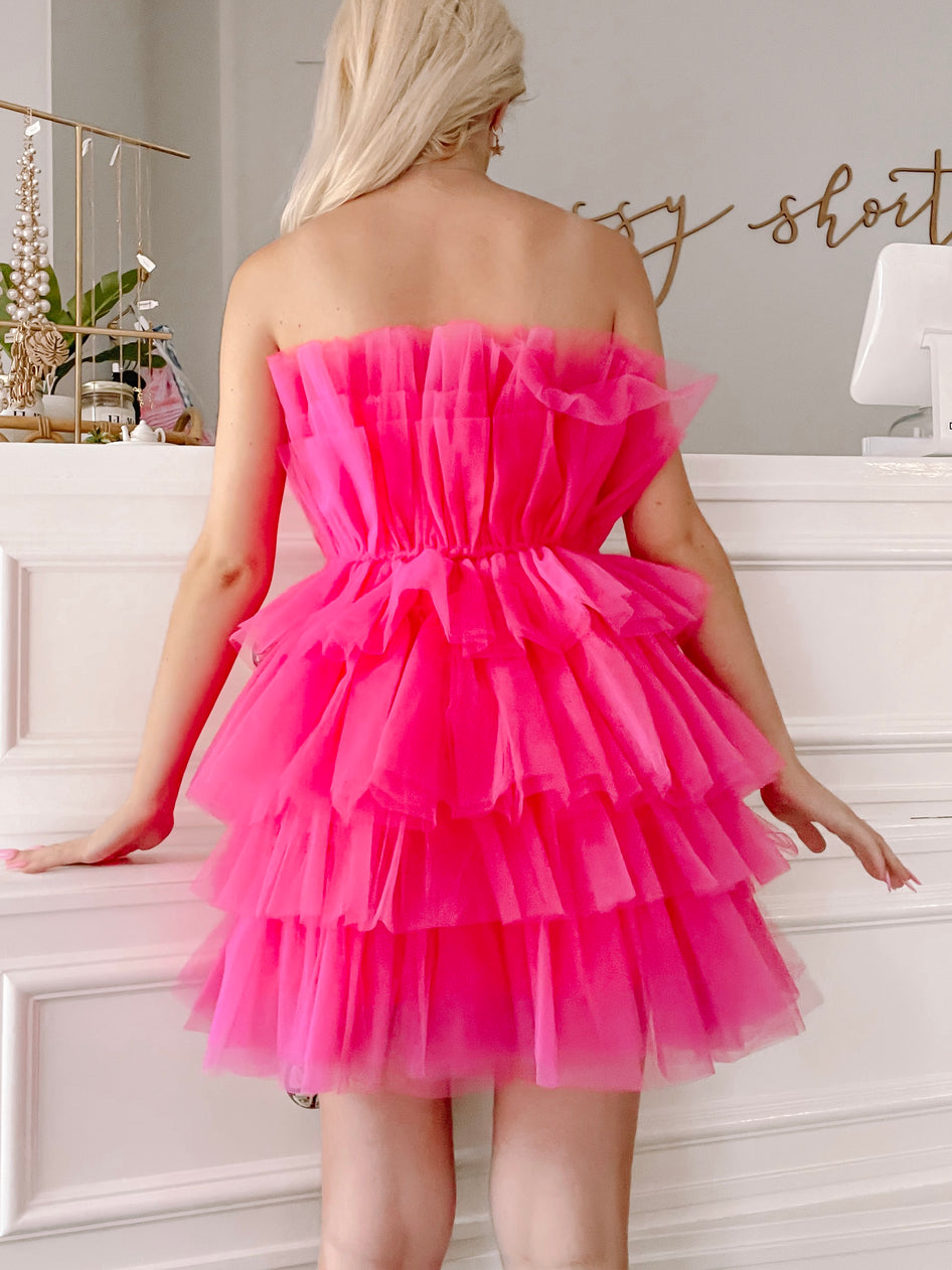 Hot pink tulle mini dress with layered ruffles, shown from the back against a white backdrop.
