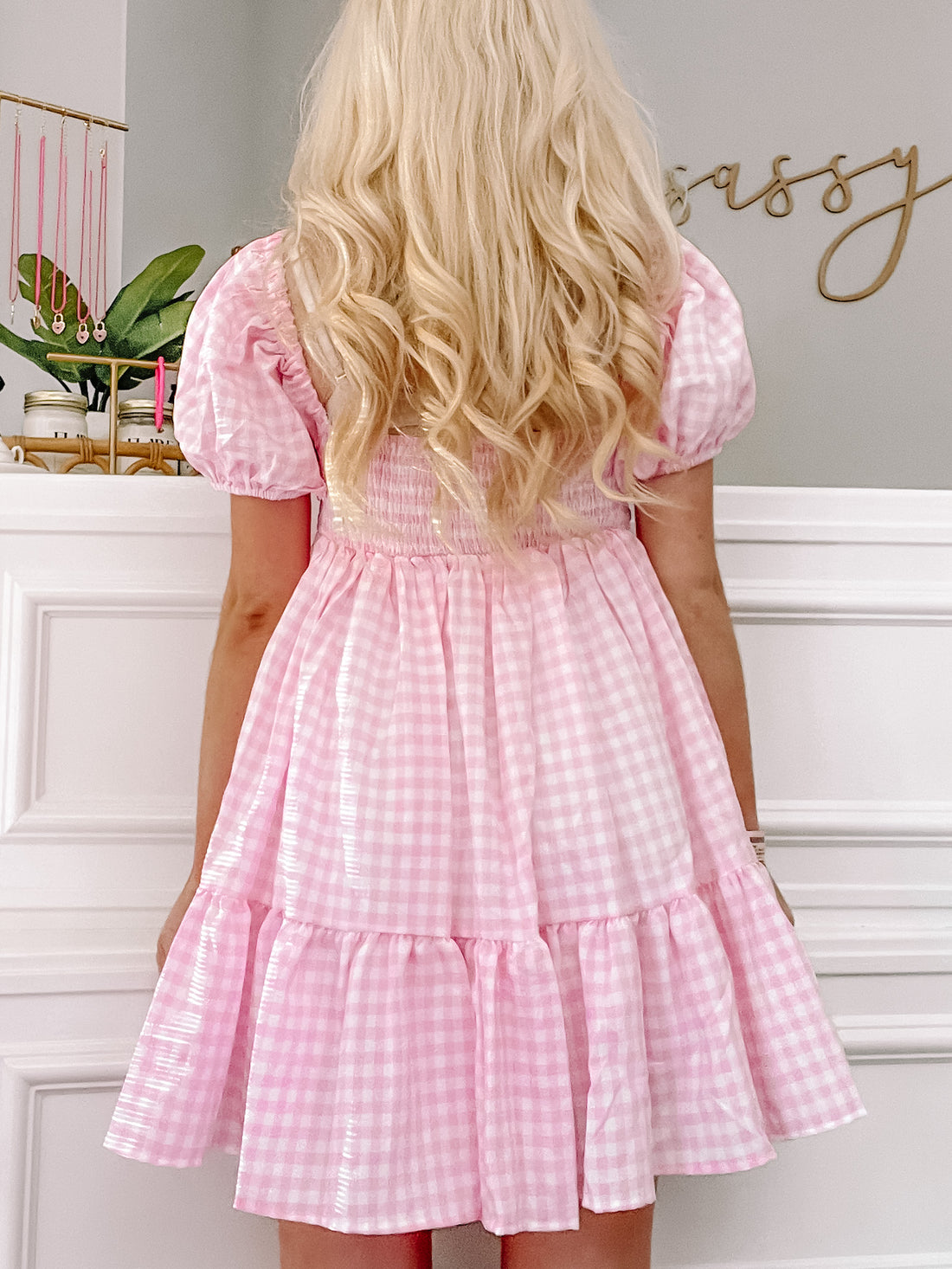 Pink gingham mini dress with puff sleeves and tiered skirt, shown from the back.
