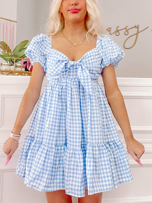 Blue gingham Pretty Privilege dress with puff sleeves and tiered skirt.
