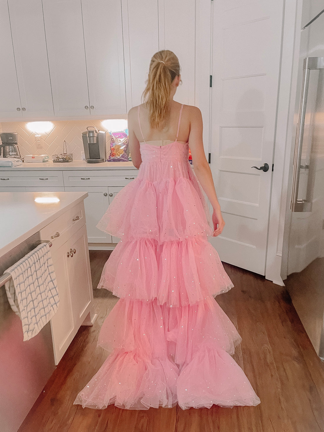 Pink sparkly tulle maxi dress with tiered ruffles, shown in a kitchen setting.
