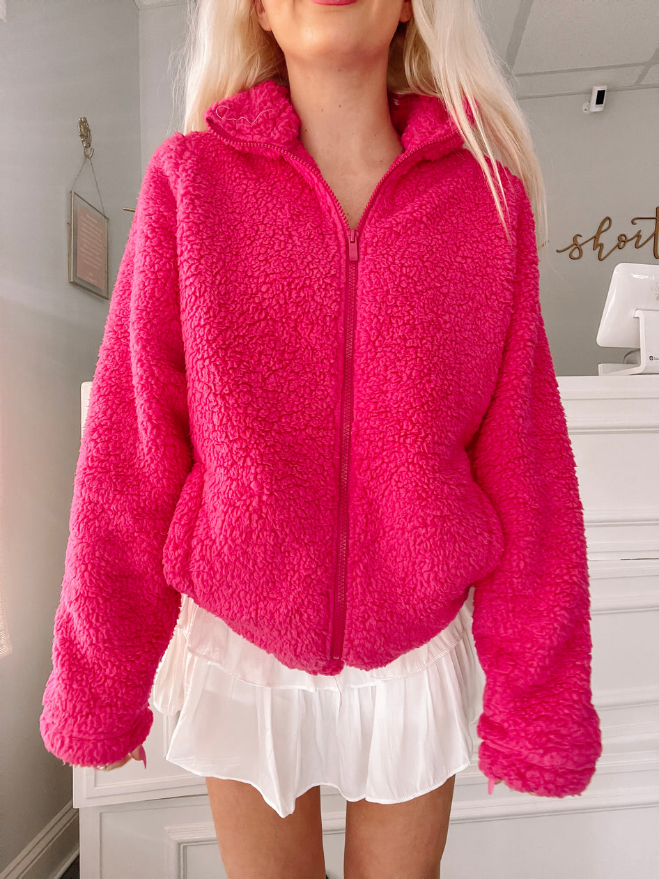 Hot pink fluffy zip-up jacket, shown on model.
