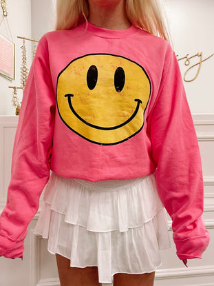 Pink Frown Upside Down Sweatshirt featuring a vintage-style yellow smiley face graphic.
