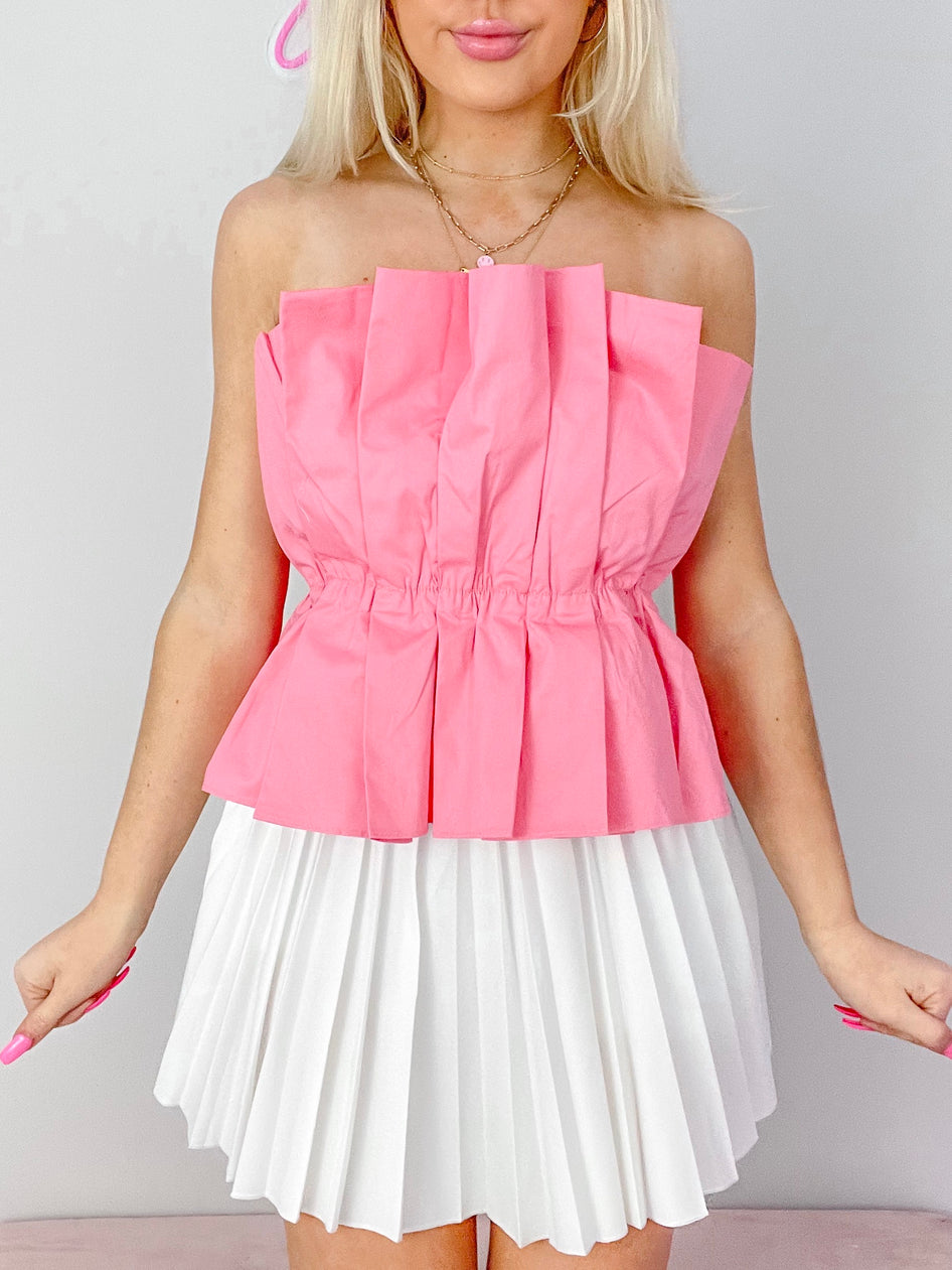Pink Modern Muse Top:  Pleated, strapless top with cinched waist, paired with white pleated mini skirt.
