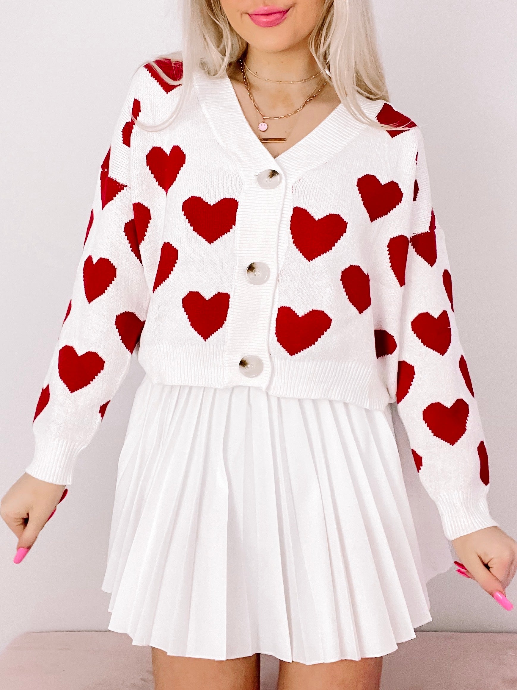 White cropped cardigan sweater with red heart pattern, button front closure.
