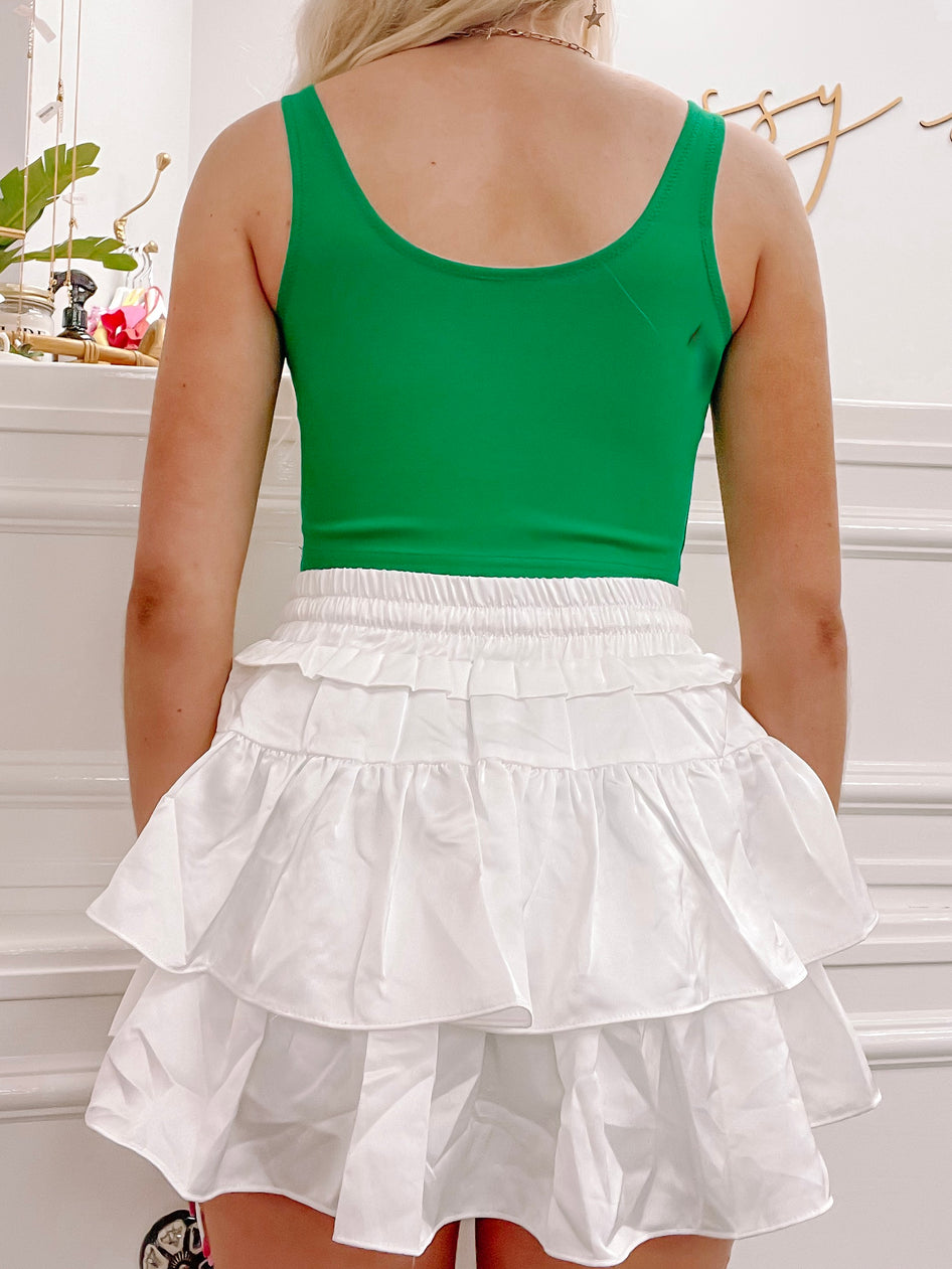 Kelly green tank top and white tiered ruffle mini skirt, back view.
