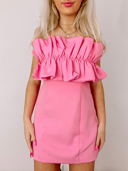 Hot pink mini dress with ruffled bodice, shown on a model against a neutral background.
