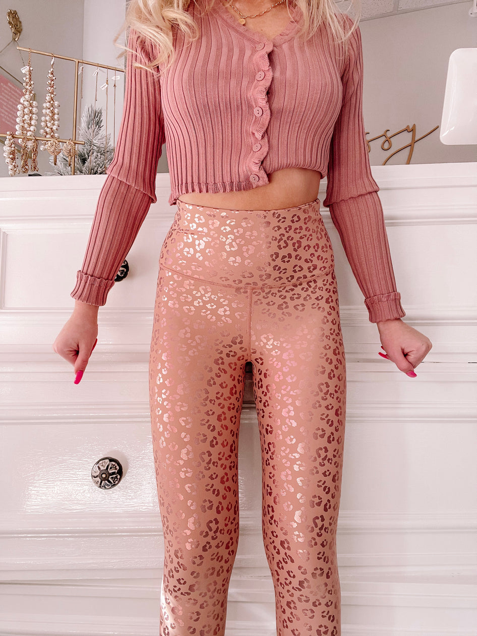 Rose gold leopard-print leggings against a white background.
