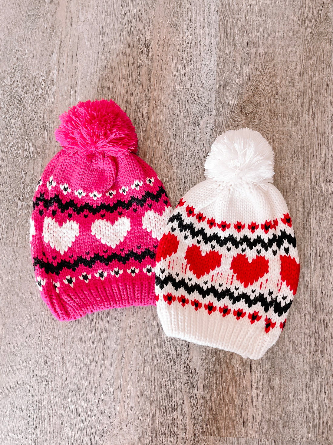 Pink & white heart-patterned Sweet Heart beanies with pom-poms.
