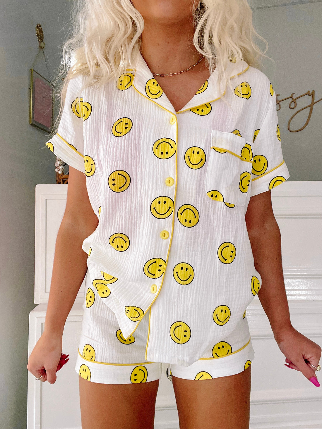 White cotton short pajama set with yellow smiley face print, button-up top and shorts.
