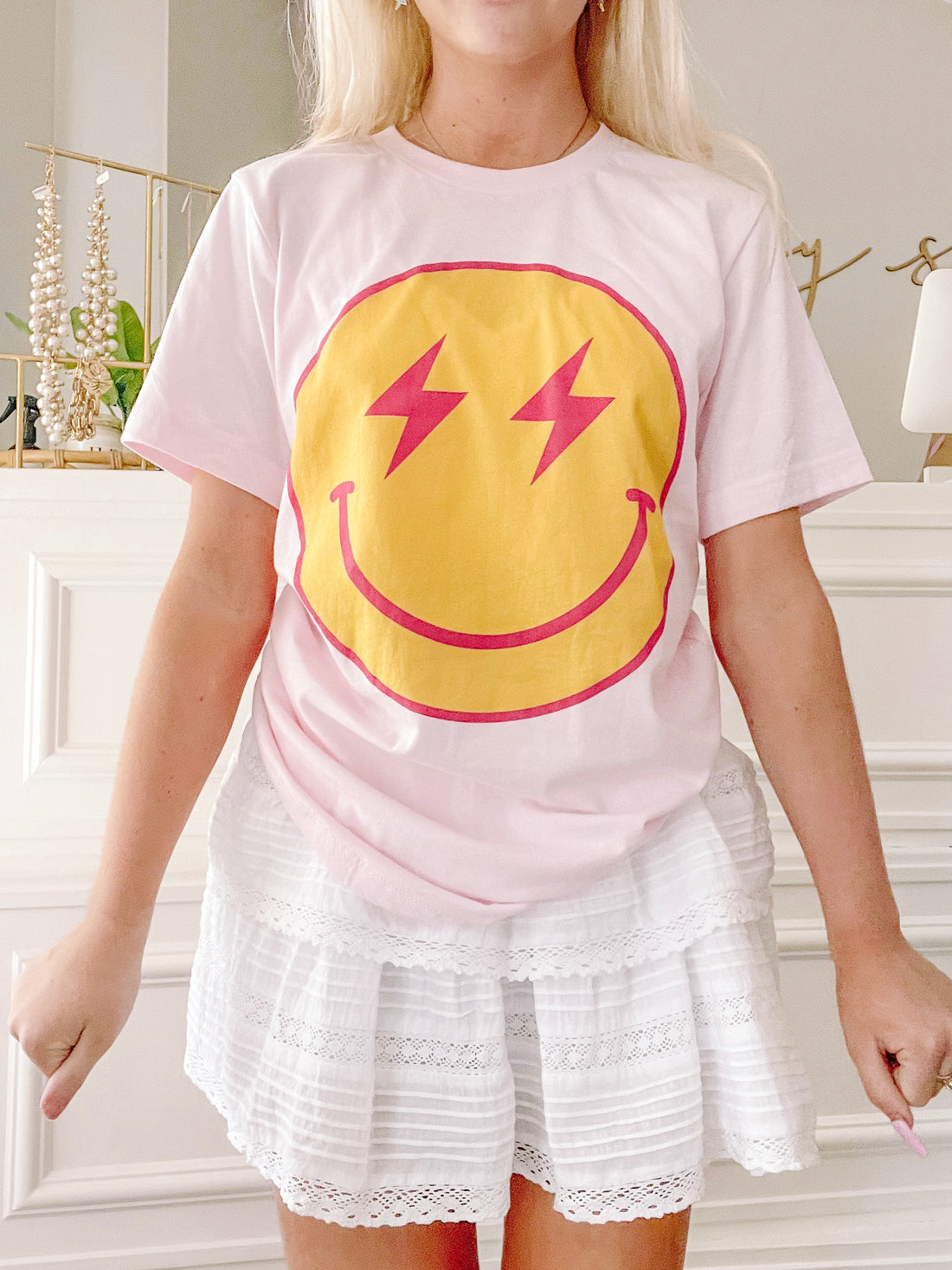 Pink Striking Smiles tee featuring a yellow smiley face with pink lightning bolts.
