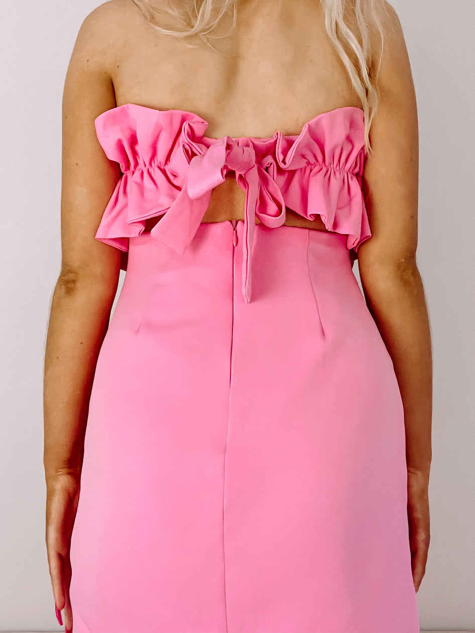 Pink mini dress with ruffled bodice and tie back detail.

