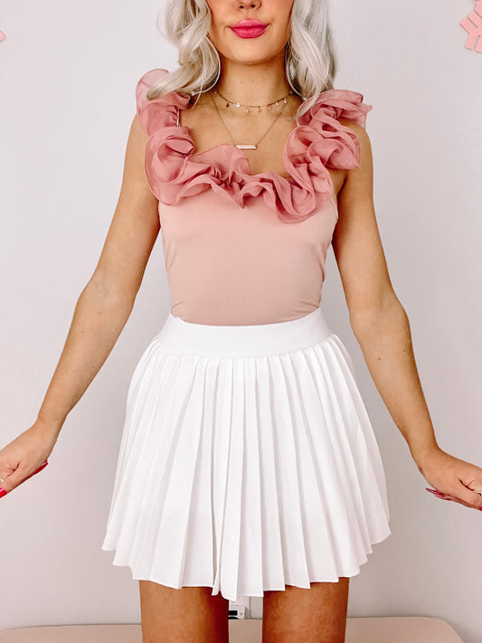 Dusty rose ruffle bodysuit paired with a white pleated mini skirt.
