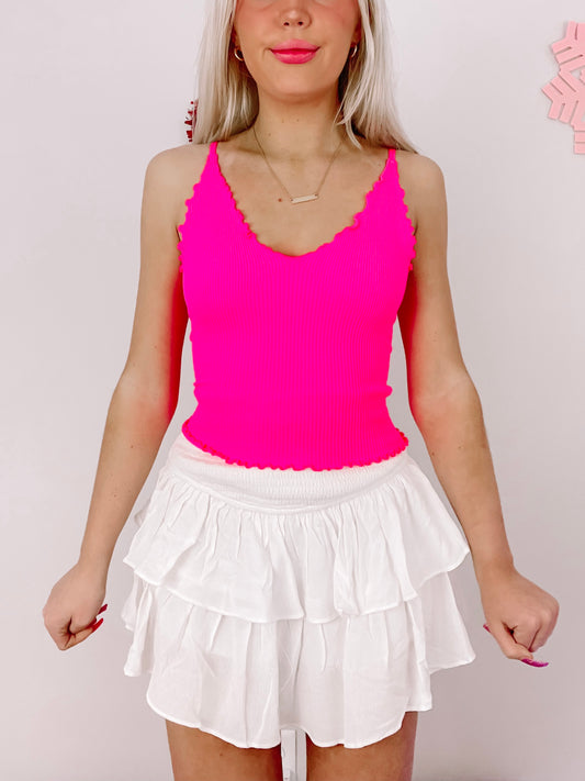 Hot pink ribbed tank top styled with a white tiered ruffle mini skirt.
