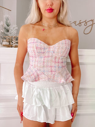 Pastel tweed cropped top with sweetheart neckline, paired with a white ruffled mini skirt.
