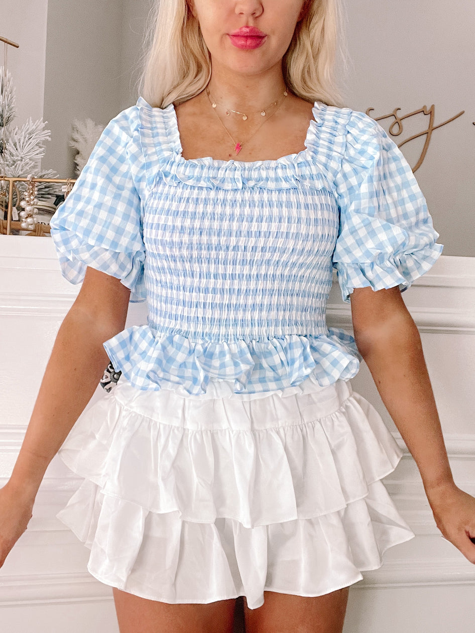 Blue Bonnet Top: Baby blue gingham smocked crop top with puff sleeves and ruffled trim.

