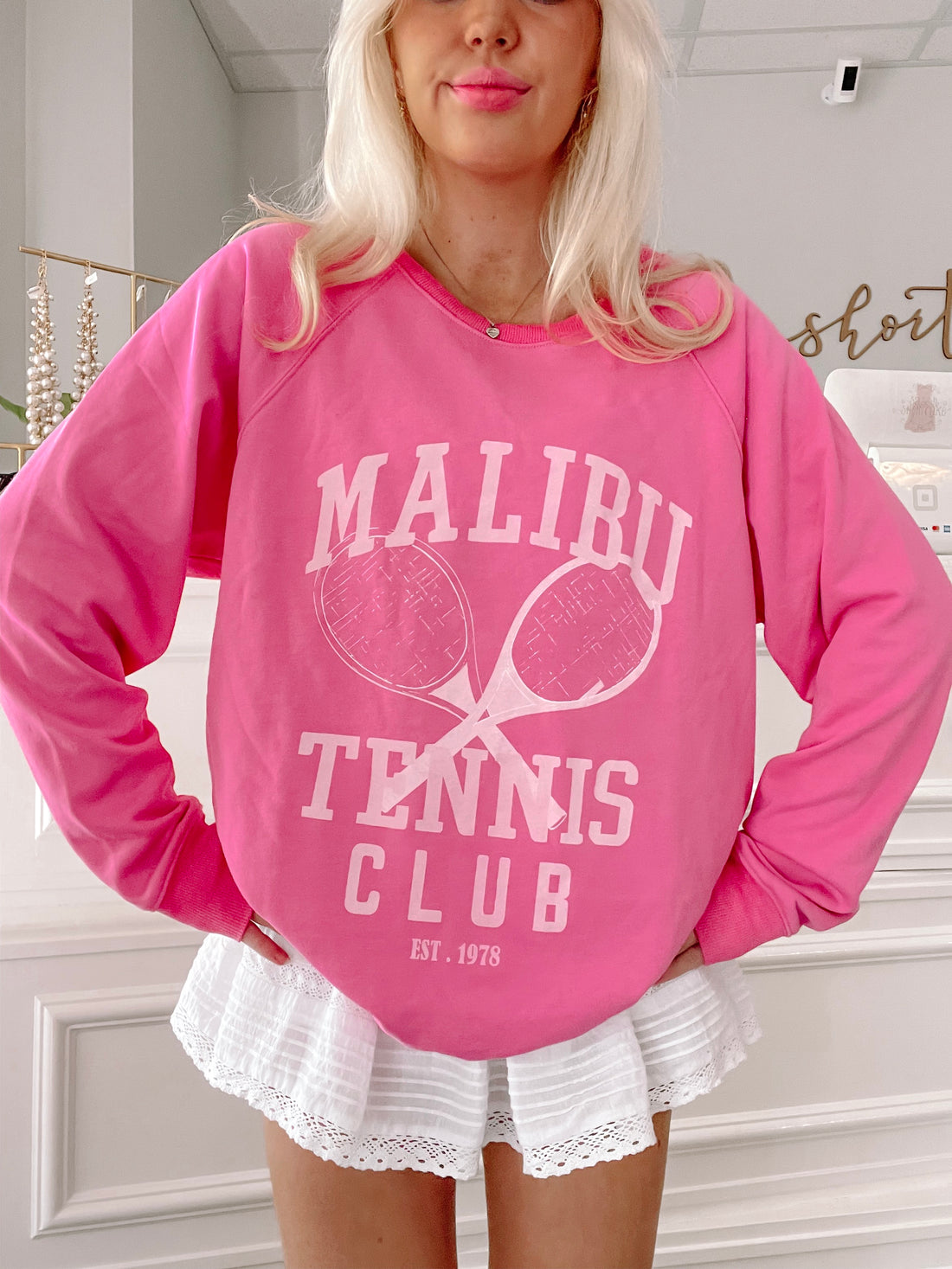 Hot pink crewneck sweatshirt featuring a tennis-themed graphic.
