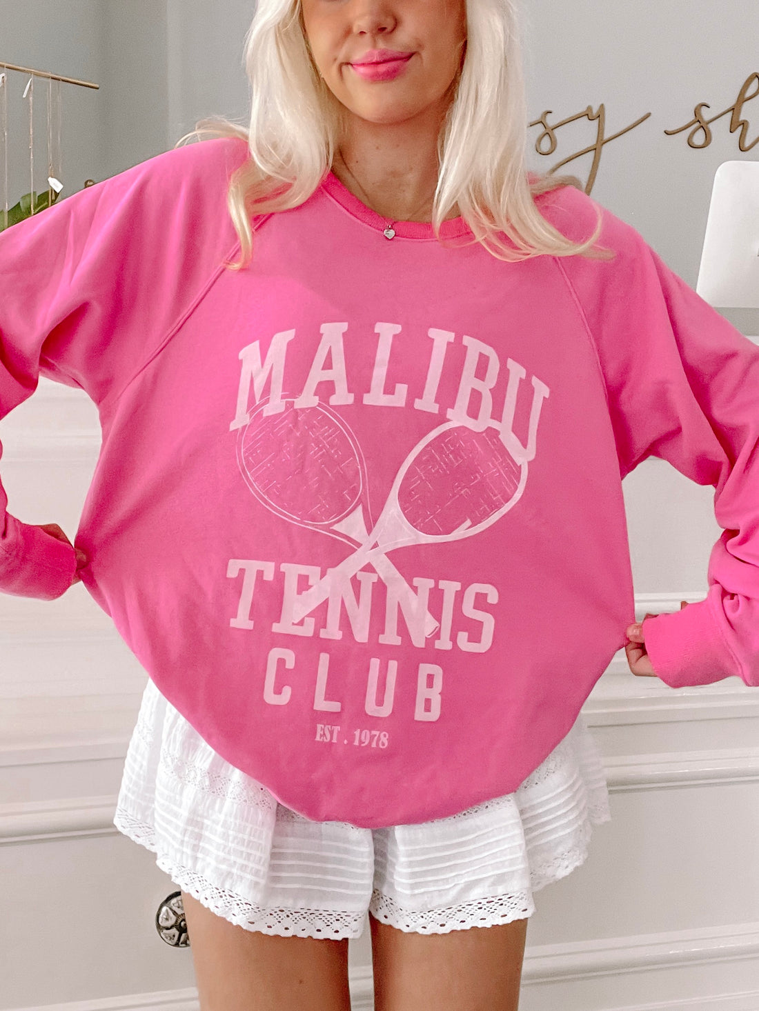 Hot pink crewneck sweatshirt with tennis racquet graphic and "Malibu Tennis Club Est. 1978" detail.
