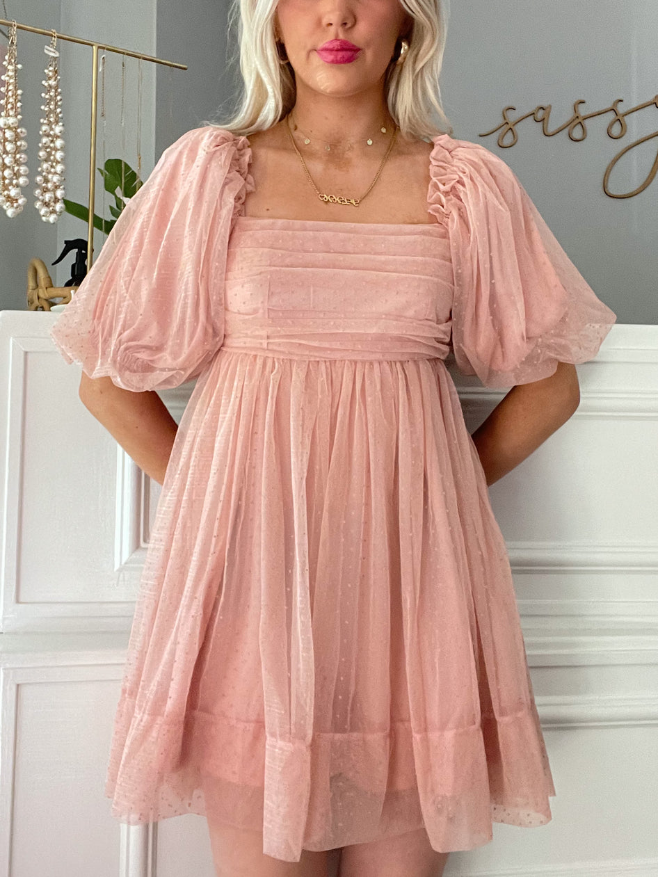 Pink Swiss dot mini dress with puff sleeves and square neckline, shown on a model.
