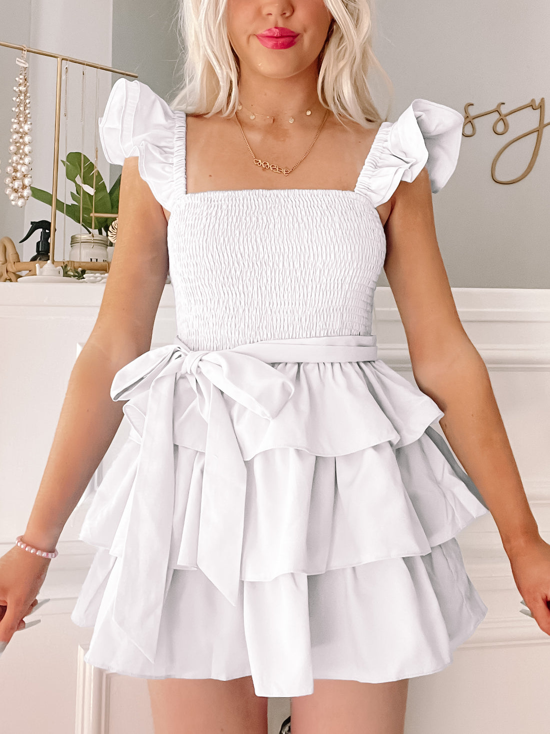 White tiered mini dress with ruffle sleeves and a self-tie belt.
