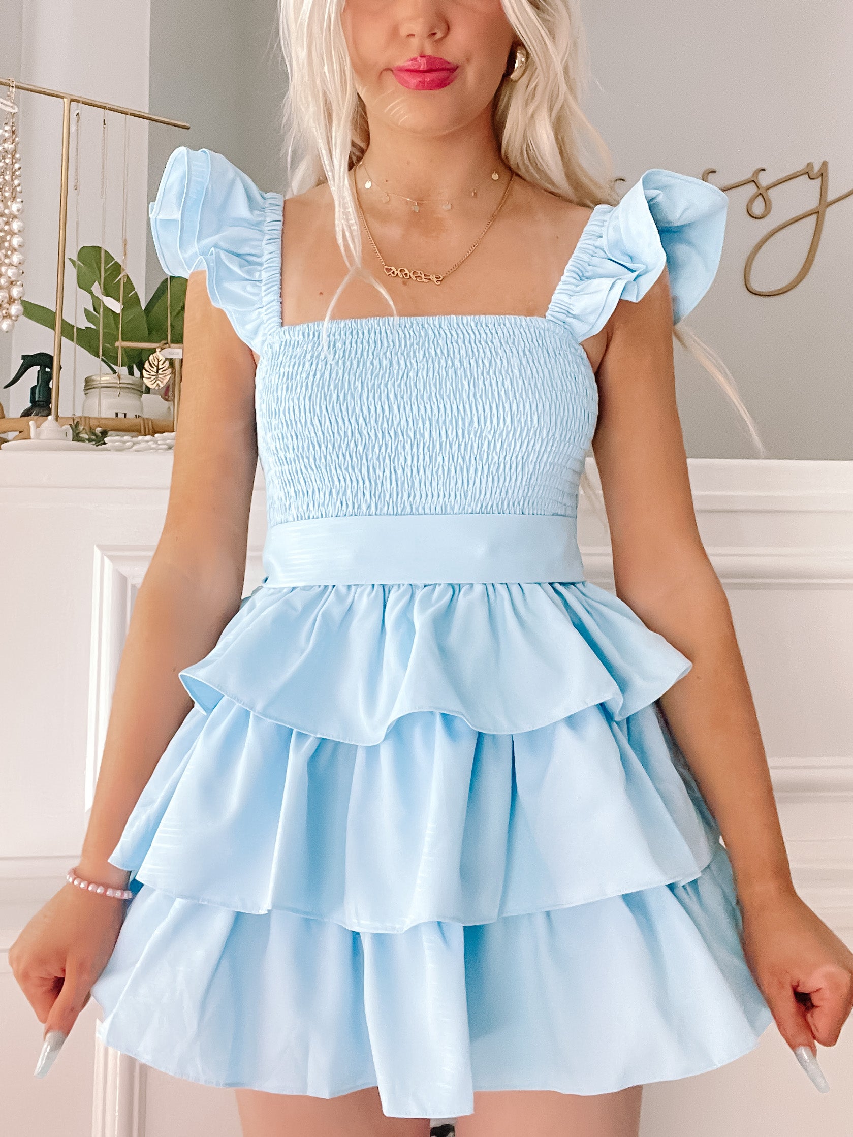 Light blue tiered mini dress with ruffle sleeves, shown on a model against a neutral background.
