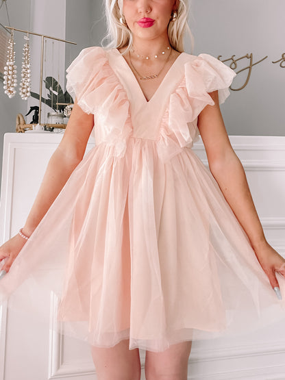 Blush pink Angel Attitude dress, featuring ruffled sleeves & tulle skirt, perfect for parties.
