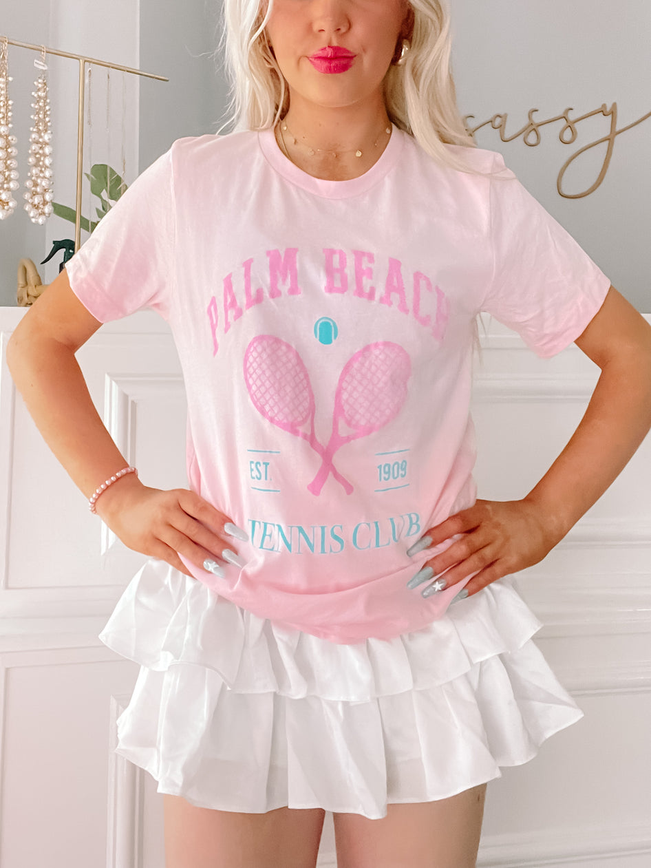 Pink tie-dye tennis tee featuring crossed rackets and Palm Beach Tennis Club graphic.
