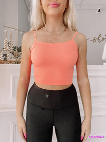 Coral ribbed tank top styled with black leggings; bright, casual summer fashion.
