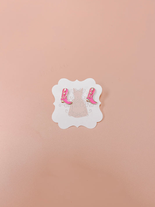 Pink cowboy boot stud earrings displayed on a light pink background.