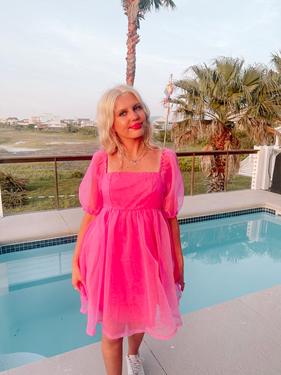 Hot pink mini dress by the pool, puff sleeves, summer fashion.
