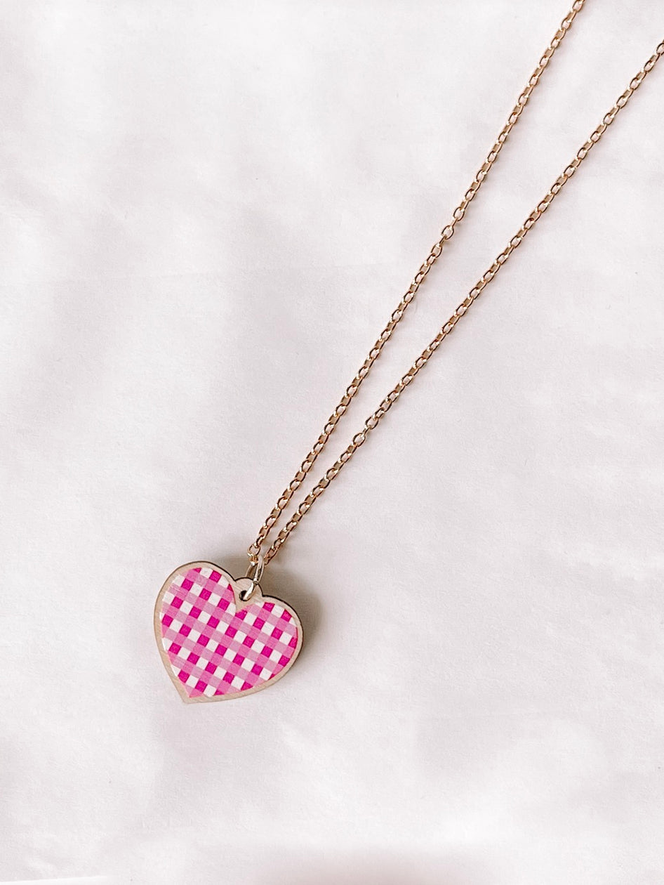 Pink gingham heart pendant necklace on gold chain.
