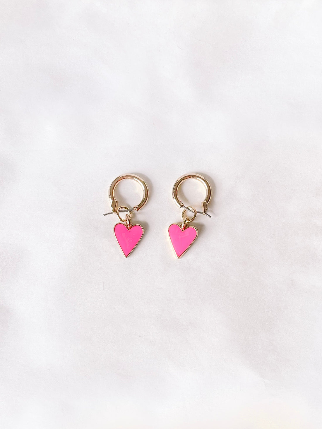 Gold hoop earrings with pink heart charms.
